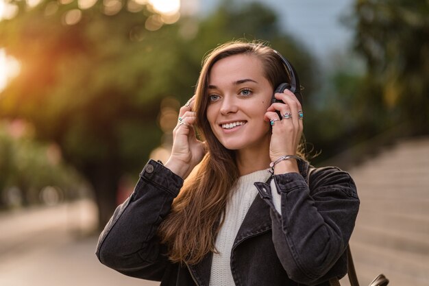 Teenager enjoys and listens to music in black wireless headphones while walking around the city