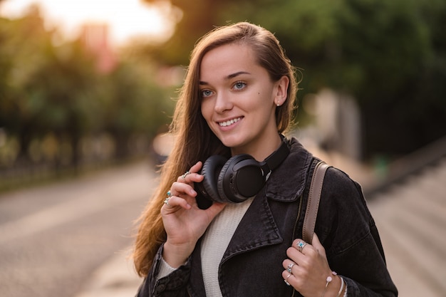 Teenager enjoys and listens to music in black wireless headphones while walking around the city