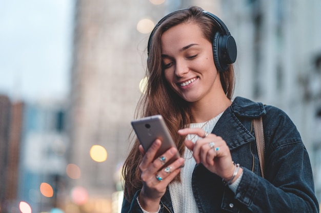 Teenager enjoys and listens to music in black wireless headphones while walking around the city