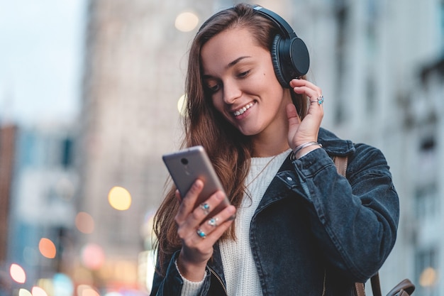 Teenager enjoys and listens to music in black wireless headphones while walking around the city