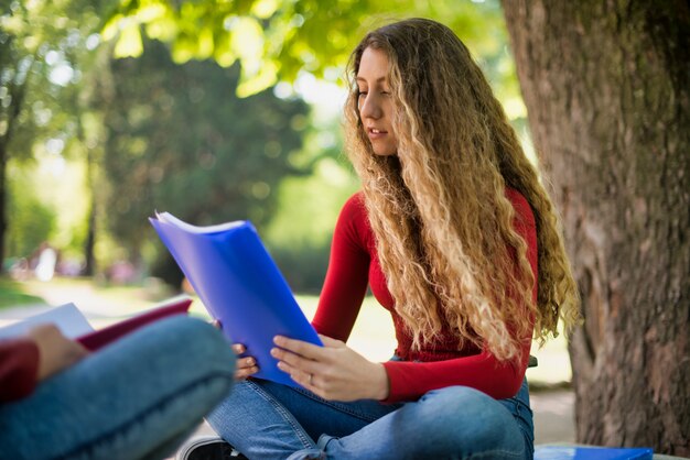 10代の女子学生が学校の公園で本を読んで