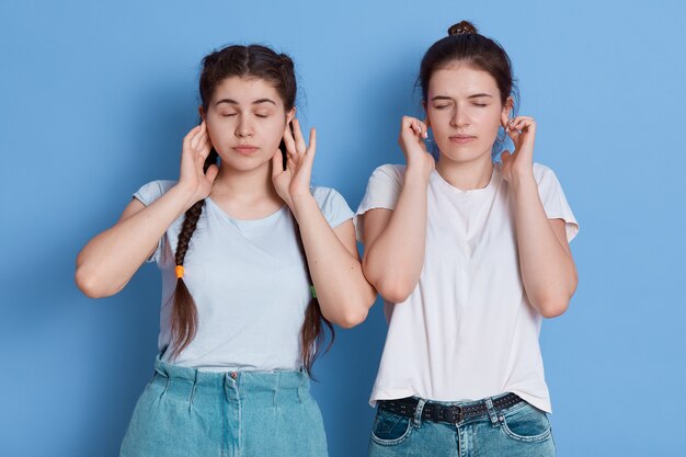 Teenager friends frustrated and covering ears with hands