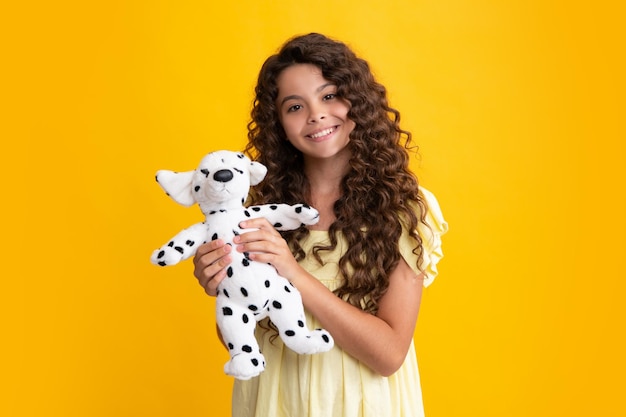 Teenager girl 12 13 14 year old hold soft toy for birthday on yellow background kid with her toys happy teenager positive and smiling emotions of teen girl