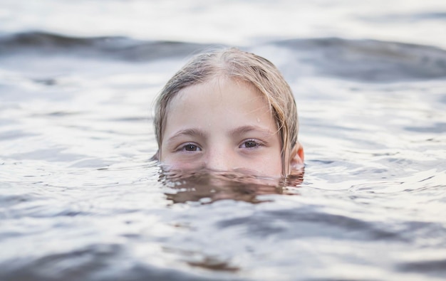 teenager girl bathes in a river and only half of her face is visible