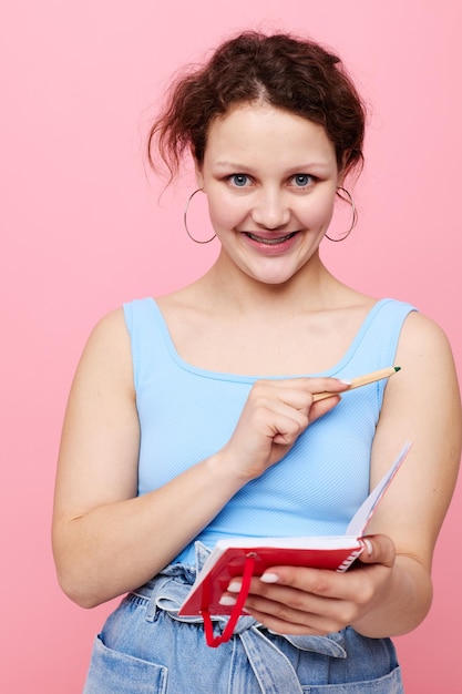 Teenager girl in a blue Tshirt with a red notepad and a pen of emotions isolated background unaltered