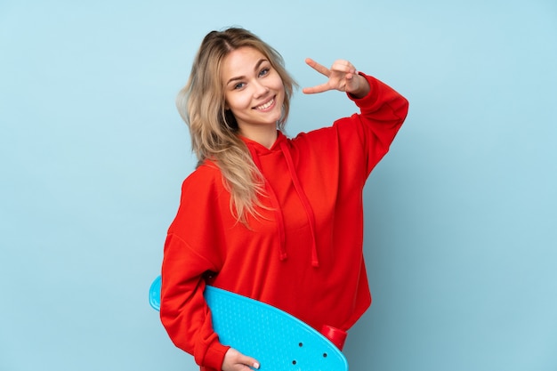 Teenager girl on blue with a skate with happy expression