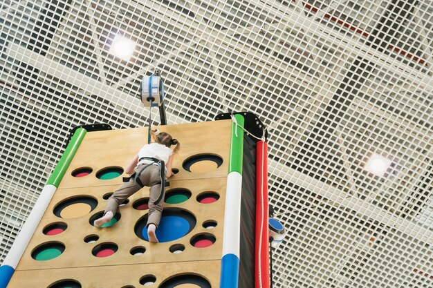 Teenager girl climbed to the top on the climbing wall,\
close-up