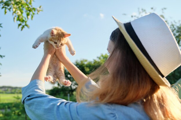 Photo teenager girl in country style denim hat holding little ginger kitten in her arms