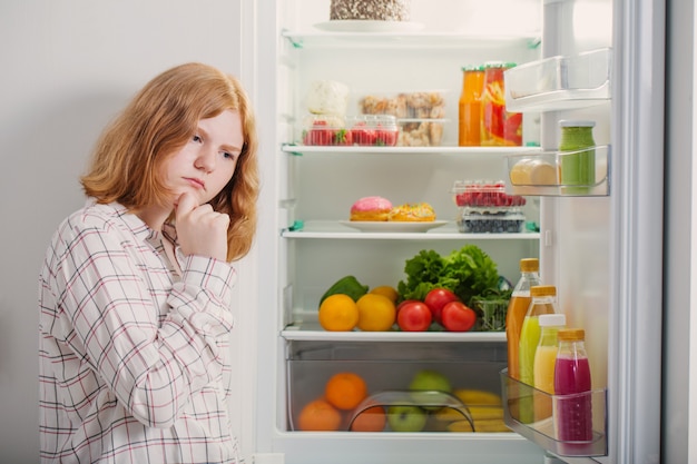 Teenager girl at fridge with food