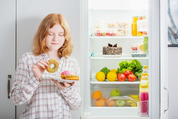 Teenager girl at fridge with food