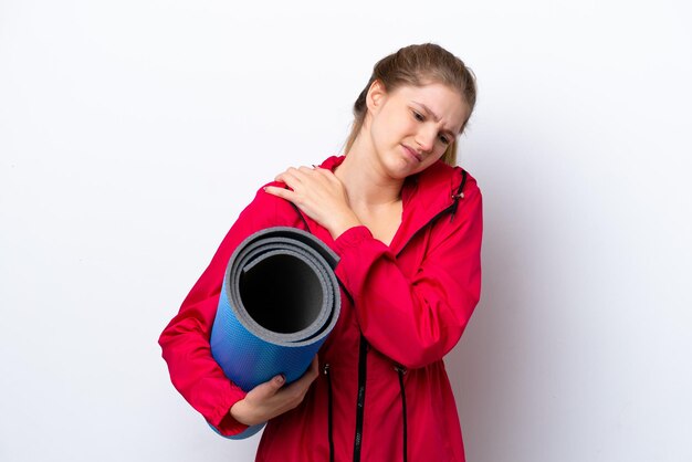 Teenager girl going to yoga classes while holding a mat isolated on white bakcground suffering from pain in shoulder for having made an effort