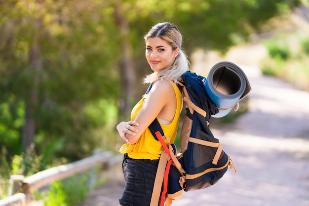 Teenager girl hiking at outdoors with arms crossed and looking forward