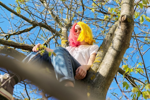 10대 소녀 힙스터가 높은 나무에 앉아 봄 자연 하늘 배경 청소년기 캐릭터 라이프스타일 행동