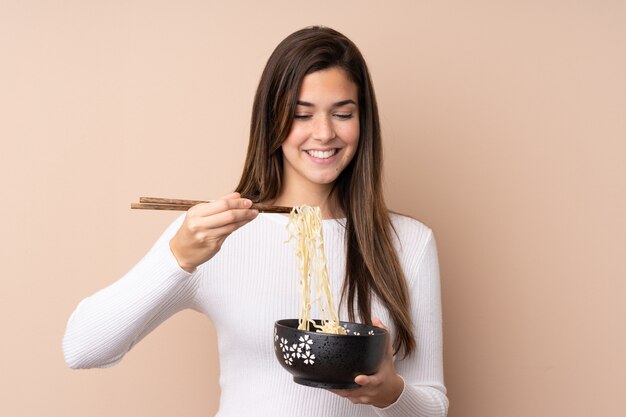 Teenager girl holding a bowl of noodles with chopsticks