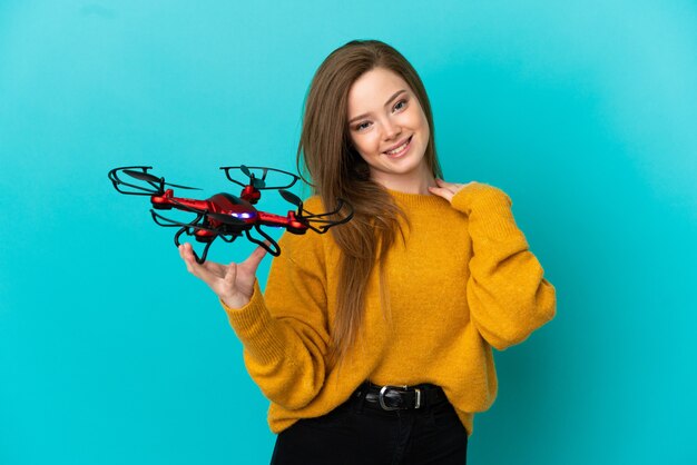 Teenager girl holding a drone over isolated blue background laughing