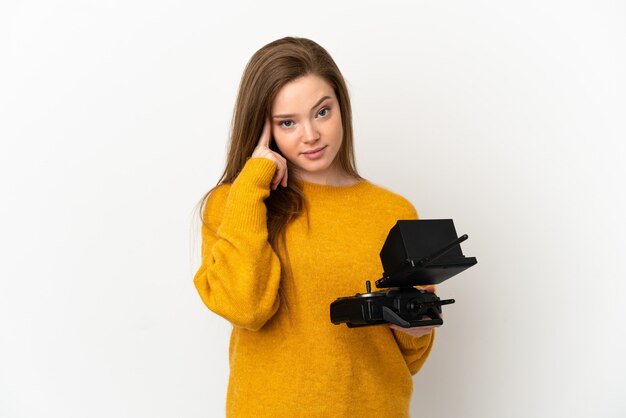 Teenager girl holding a drone remote control over isolated white background thinking an idea