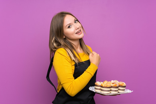 Teenager girl holding lots of different mini cakes 