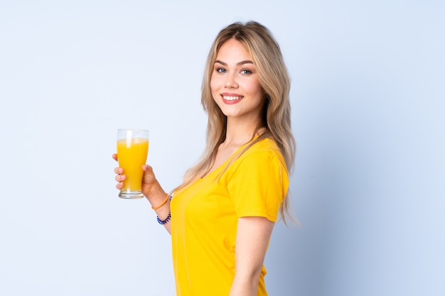 Девушка-подросток держит апельсиновый сок, много улыбаясь