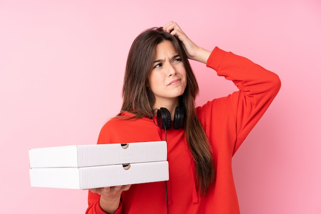 Teenager girl holding pizzas over pink wall