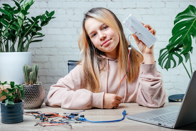 집에서 로봇 공학을 연구하는 센서 칩을 들고 있는 10대 소녀와 arduino 코딩 수업에서 ...