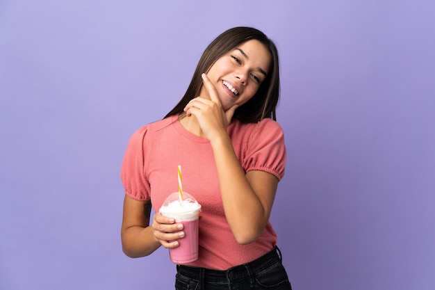 Девушка-подросток держит клубничный молочный коктейль счастлива и улыбается
