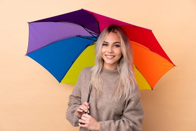 Teenager girl holding an umbrella over wall applauding