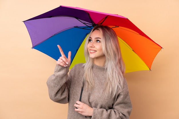 Teenager girl holding an umbrella over wall pointing with the index finger a great idea