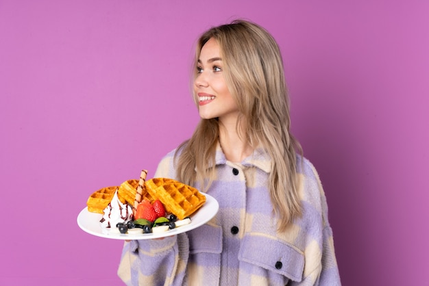 Photo teenager girl holding waffles looking side