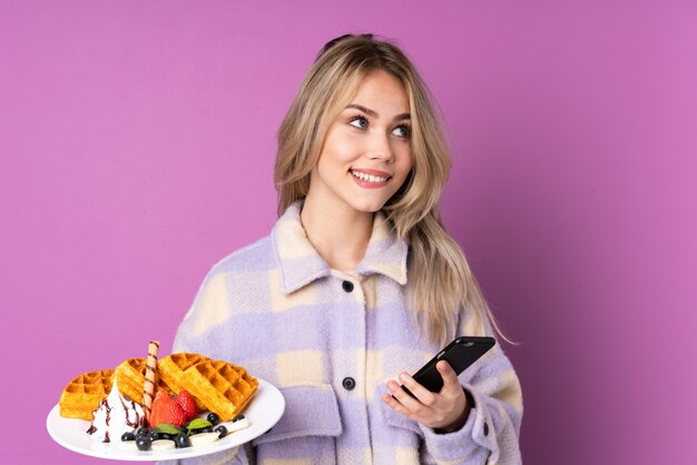 Teenager girl holding waffles and mobile phone