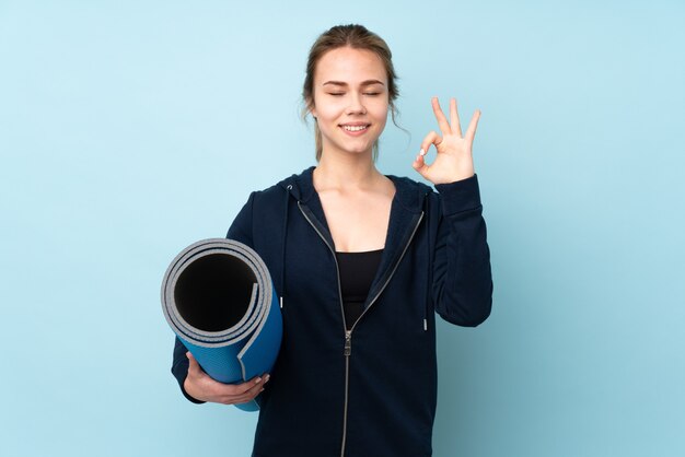 Teenager girl holding yoga mat