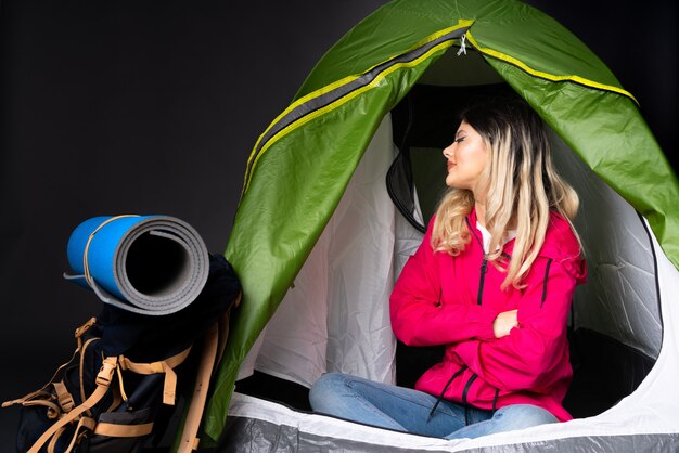 Фото Девушка-подросток в кемпинге зеленая палатка на черной стене в боковом положении