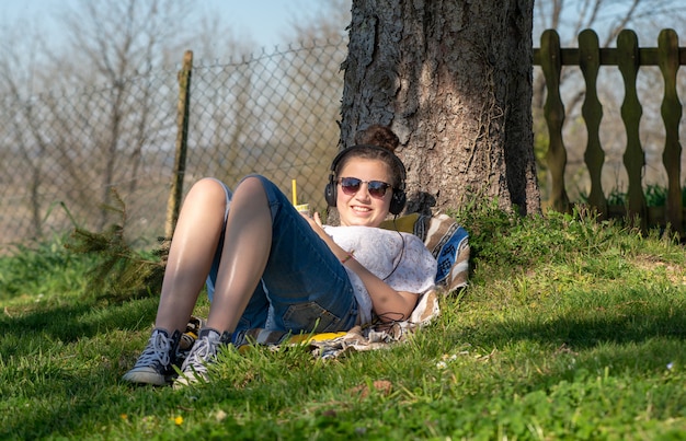 Musica d'ascolto della ragazza dell'adolescente ed acqua potabile nel parco