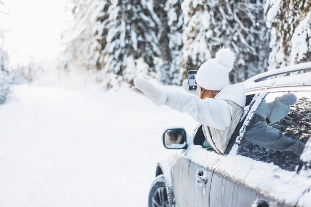 Teenager girl looking out of car window traveling in winter\
snowy forest road trip adventure and local travel concept happy\
child enjoying car ride christmas winter holidays and new year\
vacation