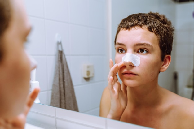 teenager girl makes cosmetic procedure for cleaning face from acne at home.