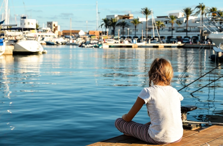 Teenager girl in meditation pose in marina of Formentera Island