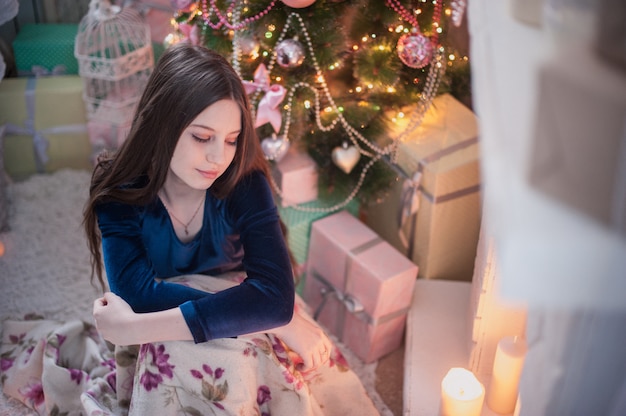 Teenager girl near the fireplace look at burning candle