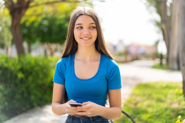 Foto ragazza dell'adolescente all'aperto facendo uso del telefono cellulare