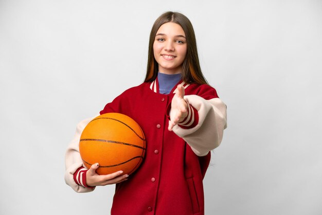 Teenager girl playing basketball over isolated white background shaking hands for closing a good deal