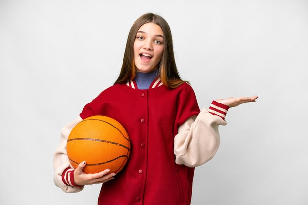 Teenager girl playing basketball over isolated white background with shocked facial expression