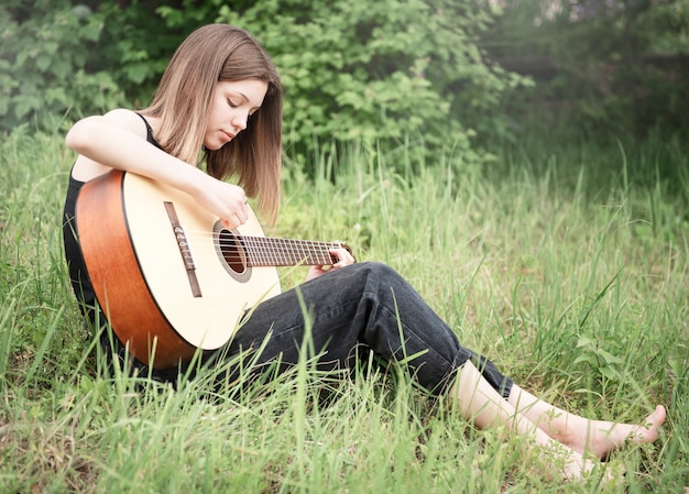 Teenager girl playing guitar in the park