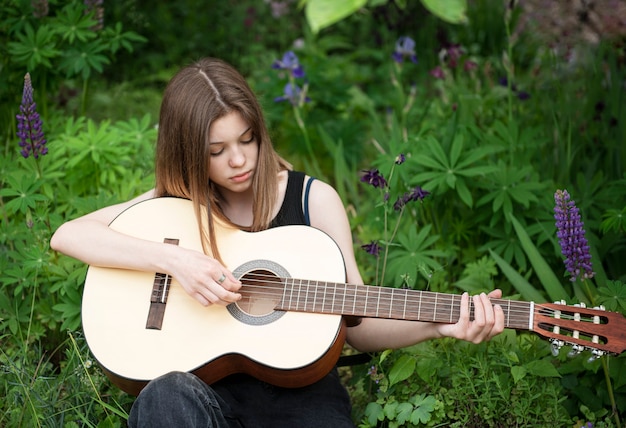 공원에서 기타를 연주하는 십 대 소녀