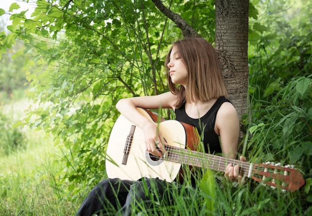 Teenager girl playing guitar in the park