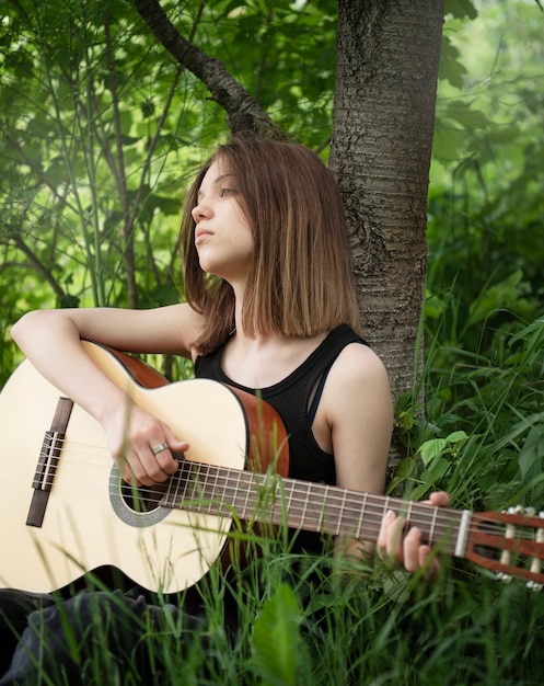 Teenager girl playing guitar in the park