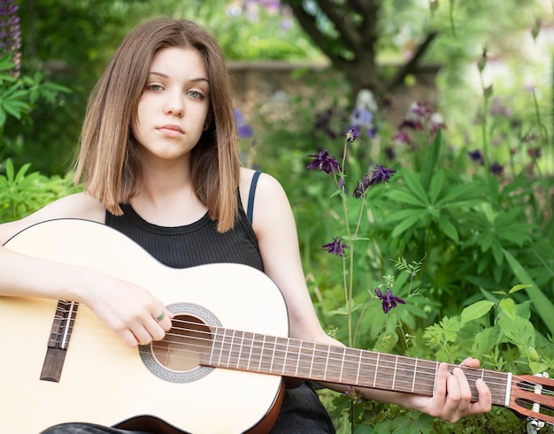 Teenager girl playing guitar in the park