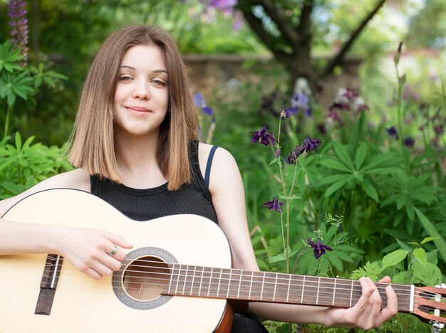 Teenager girl playing guitar in the park