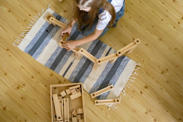 Photo teenager girl playing track constructor block tower with metallic ball maria montessori materials