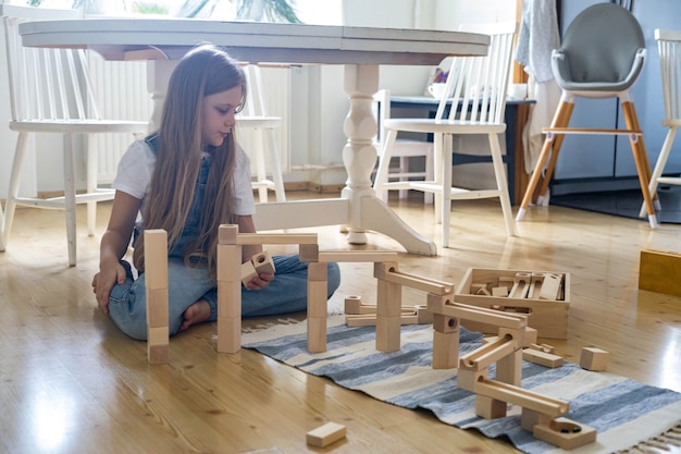 Teenager girl playing track constructor block tower with metallic ball maria montessori materials