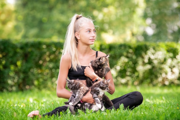 Teenager girl playing with small kittens at warm and sunny summer day