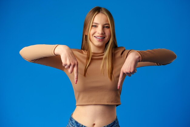Девушка-подросток указывает пальцем на копирование пространства на синем фоне