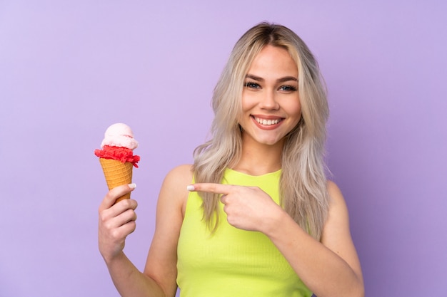 Teenager girl over purple wall and pointing it
